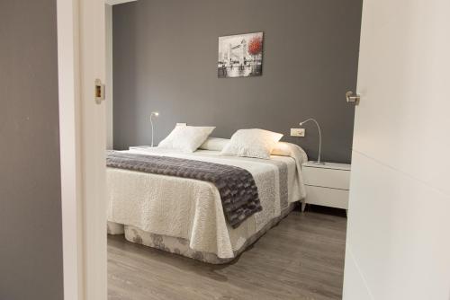 a bedroom with a bed with white sheets and pillows at Apartamentos Dacris in Jerte