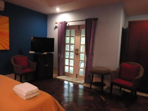 a room with a bed and chairs and a television at Saimoonbury Resort in Ban Huai Phai Yai