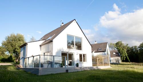a white house with glass windows on a lawn at Finn Lough in Pettigoe