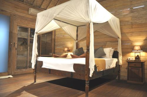 a bed with a canopy in a room at Kubudiuma Villas Bali in Canggu