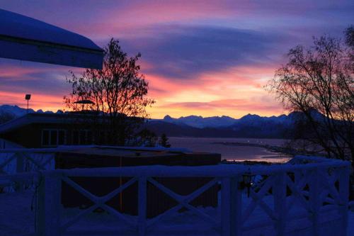 a sunset over a lake with a fence and a building at Halcyon Heights B&B/Inn in Homer