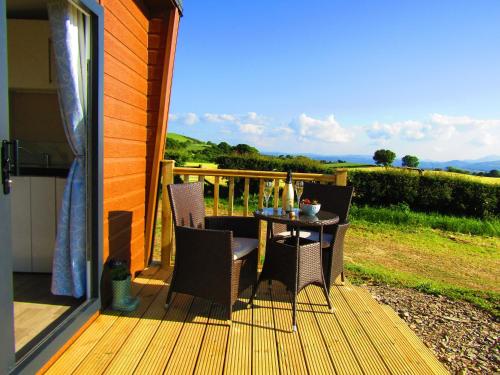 a patio with a table and chairs on a deck at Waenfechan Glamping with Hot Tubs in Colwyn Bay