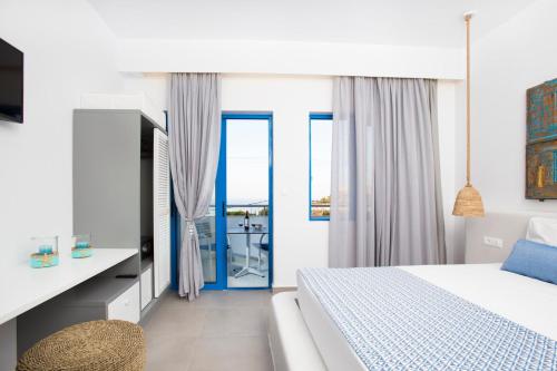 a white bedroom with a bed and a blue door at Lindos Portes Suites - Adults Only in Lindos