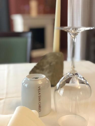 a white candle and a wine glass on a table at Villa San Carlo in Cortemilia