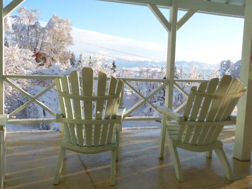 two chairs sitting on a porch with snow covered trees at Halcyon Heights B&B/Inn in Homer