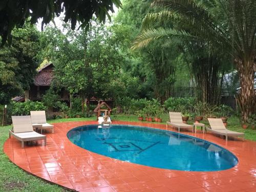 a pool in a yard with chairs and a table at Sang Tong Huts in Mae Hong Son