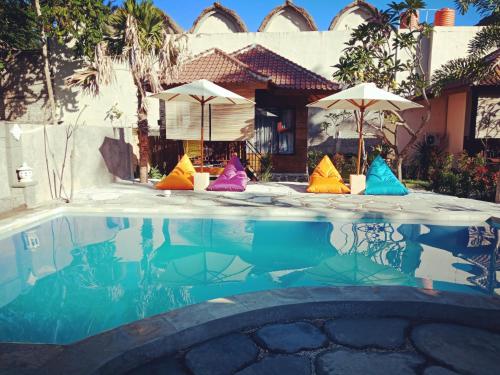 a pool with colorful chairs and umbrellas in front of a house at ZiFa Mandalika in Kuta Lombok
