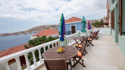 balcón con mesas y sillas y vistas al agua en Roulas Apartments, en Halki