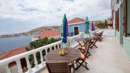 a balcony with tables and chairs and a view of the water at Roulas Apartments in Halki