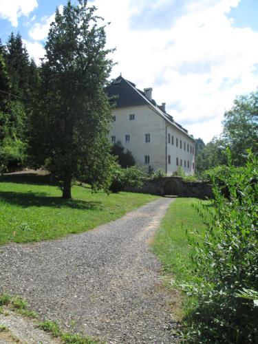 a gravel road in front of a white building at Schloss Manndorf Gästehaus in Kötschach