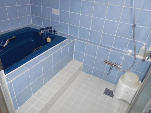 a blue tiled bathroom with a toilet and a tub at Nishikawaguchi Station Hotel Stay Lounge in Kawaguchi