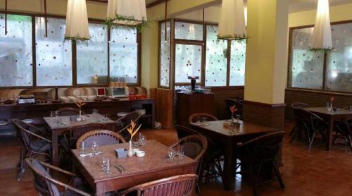 een eetkamer met tafels en stoelen en ramen bij The Camelot Beach Resort - Baga in Baga