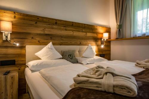 two white beds in a room with a wooden wall at La Bercia Alpine Lodge & Spa in La Villa