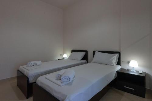 two beds in a room with white sheets and towels at Grand Suites with Private Pools in Kalamata