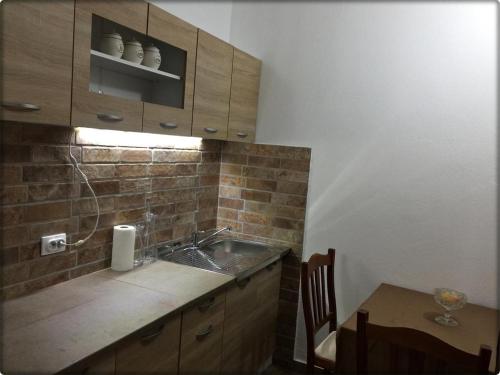 a kitchen with a sink and a table with a chair at Apartmani Labovic in Budva