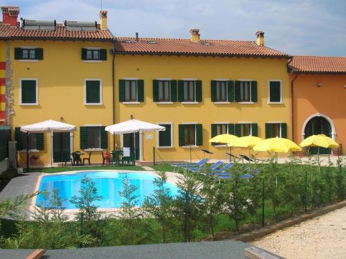 una gran casa amarilla con piscina y sombrillas en Agriturismo Colombarola, en Sona