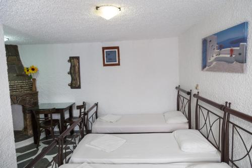 a room with three beds and a table and a table at Studio Eleni in Mýkonos City