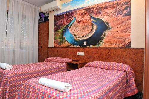 two beds in a hotel room with a painting on the wall at Hostal Venecia in Azagra