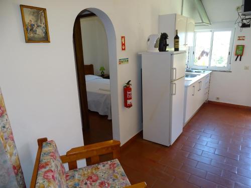 a kitchen with a refrigerator and a room with a bed at Falfeira Apartments in Lagos