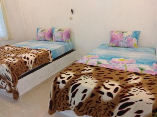 two beds in a room with a leopard print bed at Nanda Homestay in Kuta Lombok