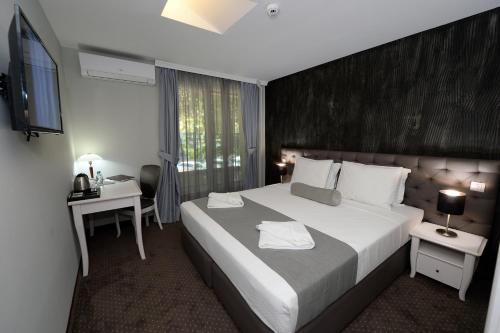 a hotel room with a large bed and a desk at Hotel Alexandar II in Skopje