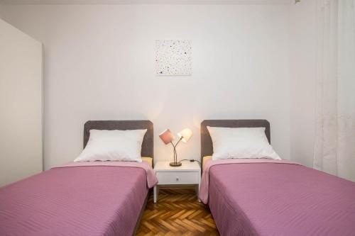 two beds sitting next to each other in a room at Apartman Šesna in Bol
