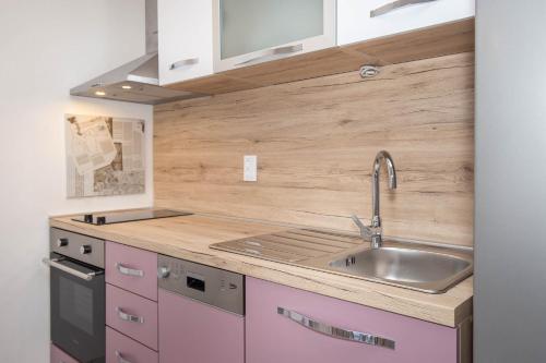 a kitchen with pink cabinets and a sink at Apartman Šesna in Bol
