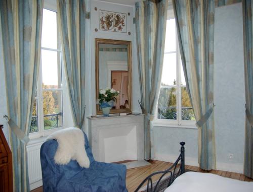 Zimmer mit einem blauen Stuhl und 2 Fenstern in der Unterkunft Domaine de Gondrange - Chambres d'Hôtes in Havange