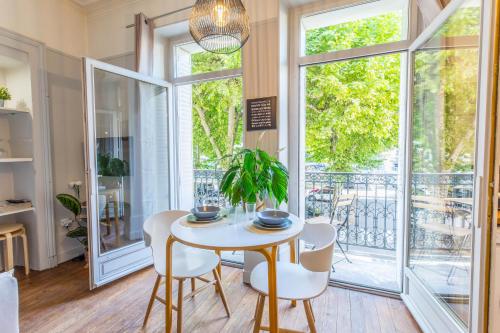 a dining room with a table and chairs and large windows at Studio Clemenceau in Aix-les-Bains