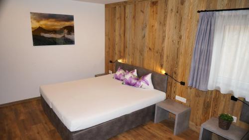 ein Schlafzimmer mit einem weißen Bett mit lila Kissen in der Unterkunft Apartment Wandspitz in Hintertux