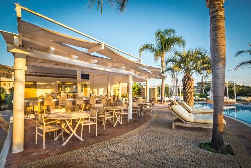 a patio with tables and chairs next to a pool at Parthenis Hotel & Suites in Malia