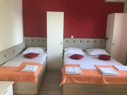 two beds in a room with red walls at Apartments Nela in Jesenice
