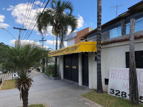 un bâtiment avec un auvent jaune et des palmiers dans l'établissement Hotel Pousada Marista, à Goiânia