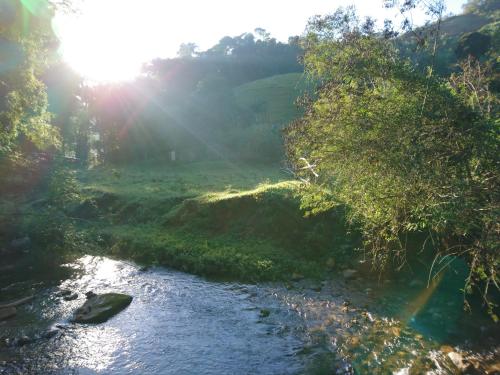 a river in a field with the sun shining at Casa do Artista in Lumiar