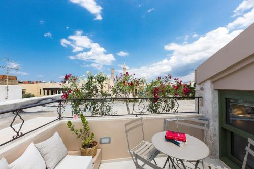 a balcony with a table and chairs and flowers at Neratze Hammam Suites in Rethymno Town