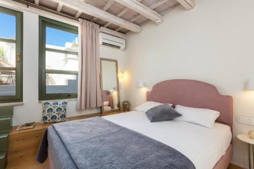 a bedroom with a bed and a large window at Neratze Hammam Suites in Rethymno Town