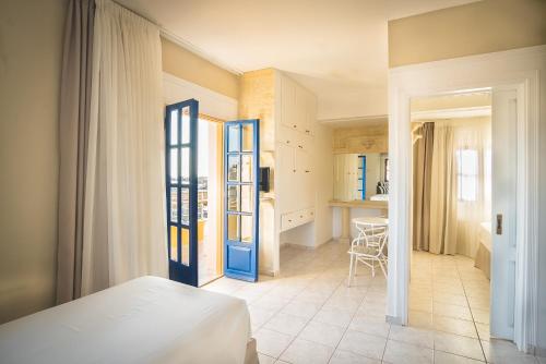 a bedroom with a bed and a room with a kitchen at Parthenis Hotel & Suites in Malia