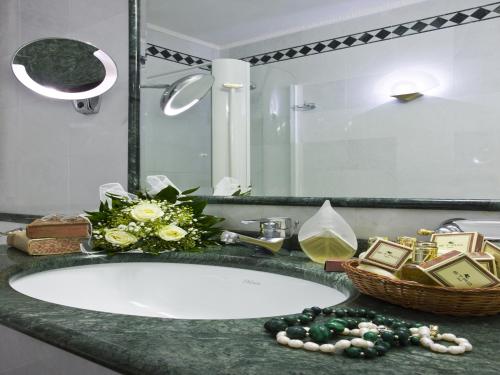a bathroom sink with a basket of flowers and a mirror at Hotel Vittoria in Pesaro
