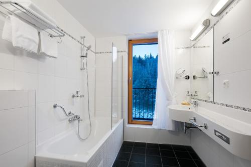a bathroom with a tub and a sink and a window at Hotel Ostrov in Tisá