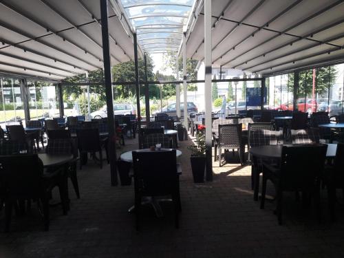 a dining room with tables and chairs and a lot of windows at Hotel Restaurant Hellas in Gelting