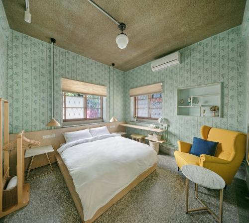 a bedroom with a large bed and a yellow chair at Civil Life Tainan in Tainan