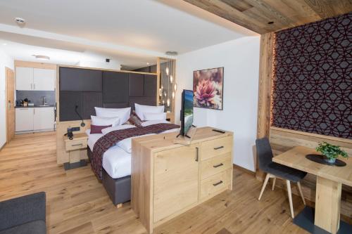 a bedroom with a bed and a desk with a television at Wagner's Aparthotel in Pertisau
