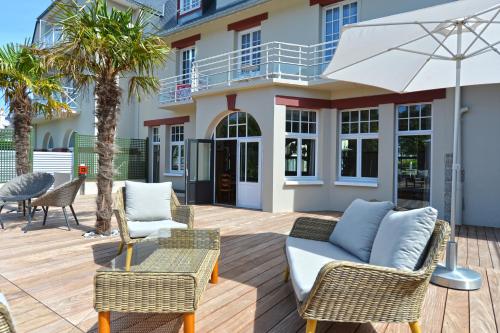 a patio with chairs and tables and an umbrella at Hotel De Diane in Sables-dʼOr-les-Pins