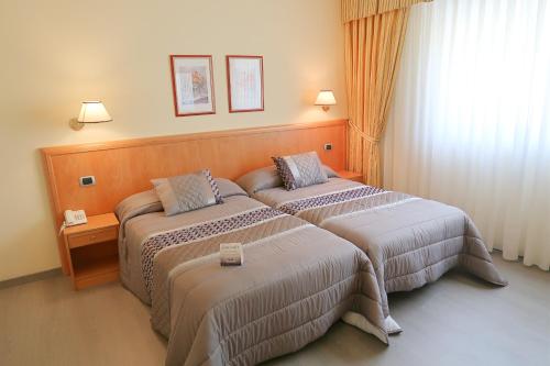 a hotel room with two beds and a window at Hotel O Camiño in O Barco de Valdeorras