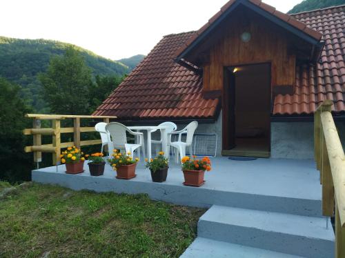 two white chairs and flowers on a porch of a house at Apartment Sela in Tolmin
