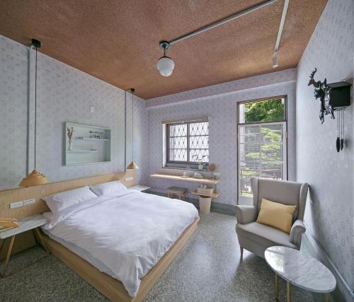 a bedroom with a large bed and a chair at Civil Life Tainan in Tainan