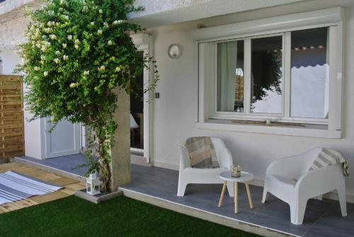 a patio with two chairs and a tree at L Abri-côtier Appartements in Saintes-Maries-de-la-Mer