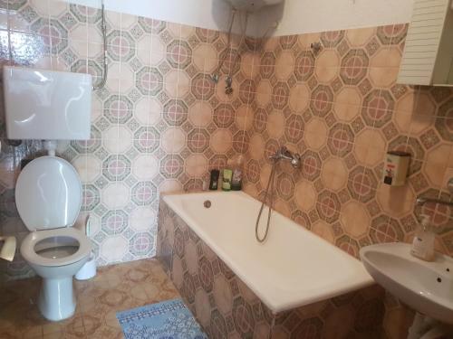 a bathroom with a toilet and a tub and a sink at Guest House Alisa in Hvar