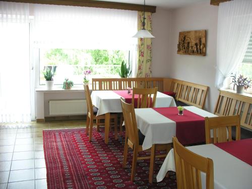 ein Esszimmer mit Tischen, Stühlen und einem Fenster in der Unterkunft Weingut & Gästehaus Mees in Briedel