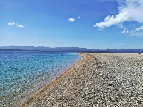 a beach with blue water and mountains in the background at Formula Fortunae BOL in Bol